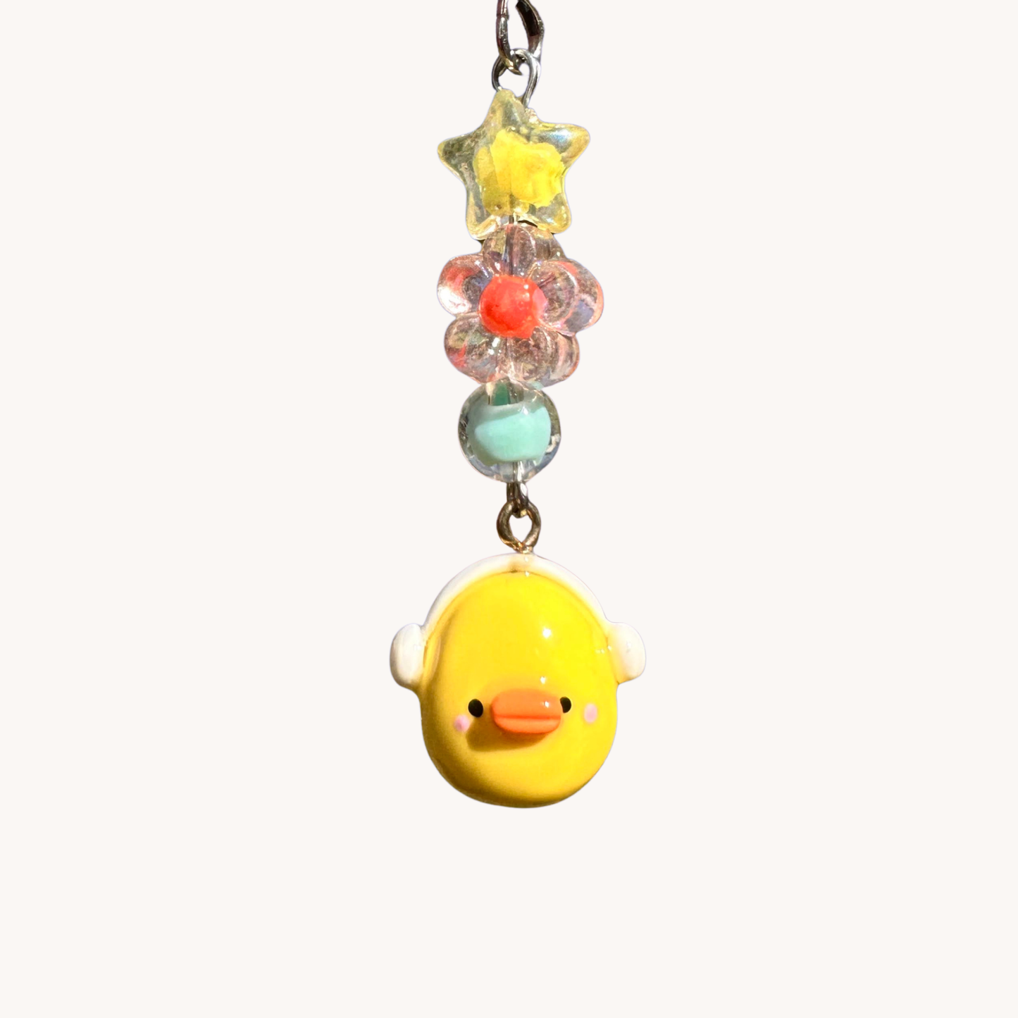 Yellow duck charm with headphones with colorful beads on a white background