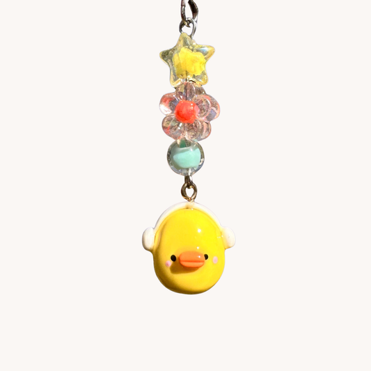 Yellow duck charm with headphones with colorful beads on a white background