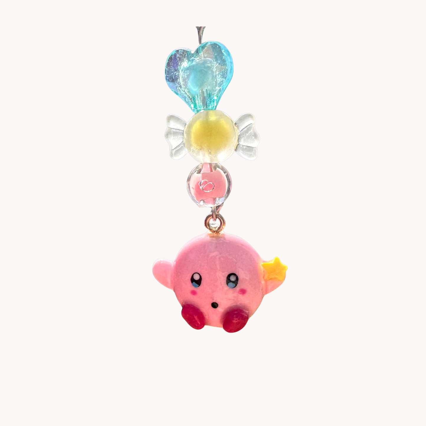 Colorful charm with clay kirby character and heart-shaped top on a white background