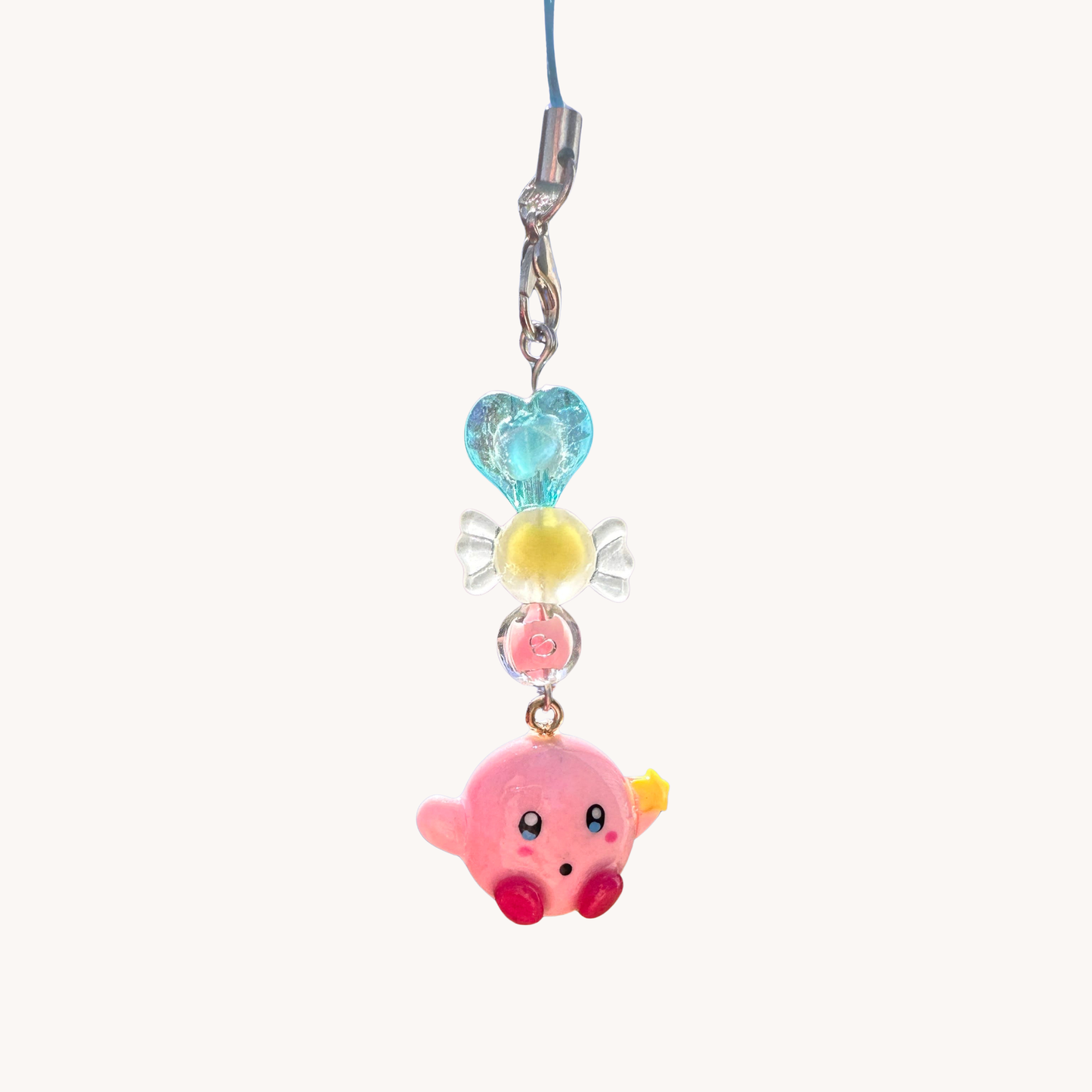 Colorful charm with clay kirby character and heart-shaped top on a white background