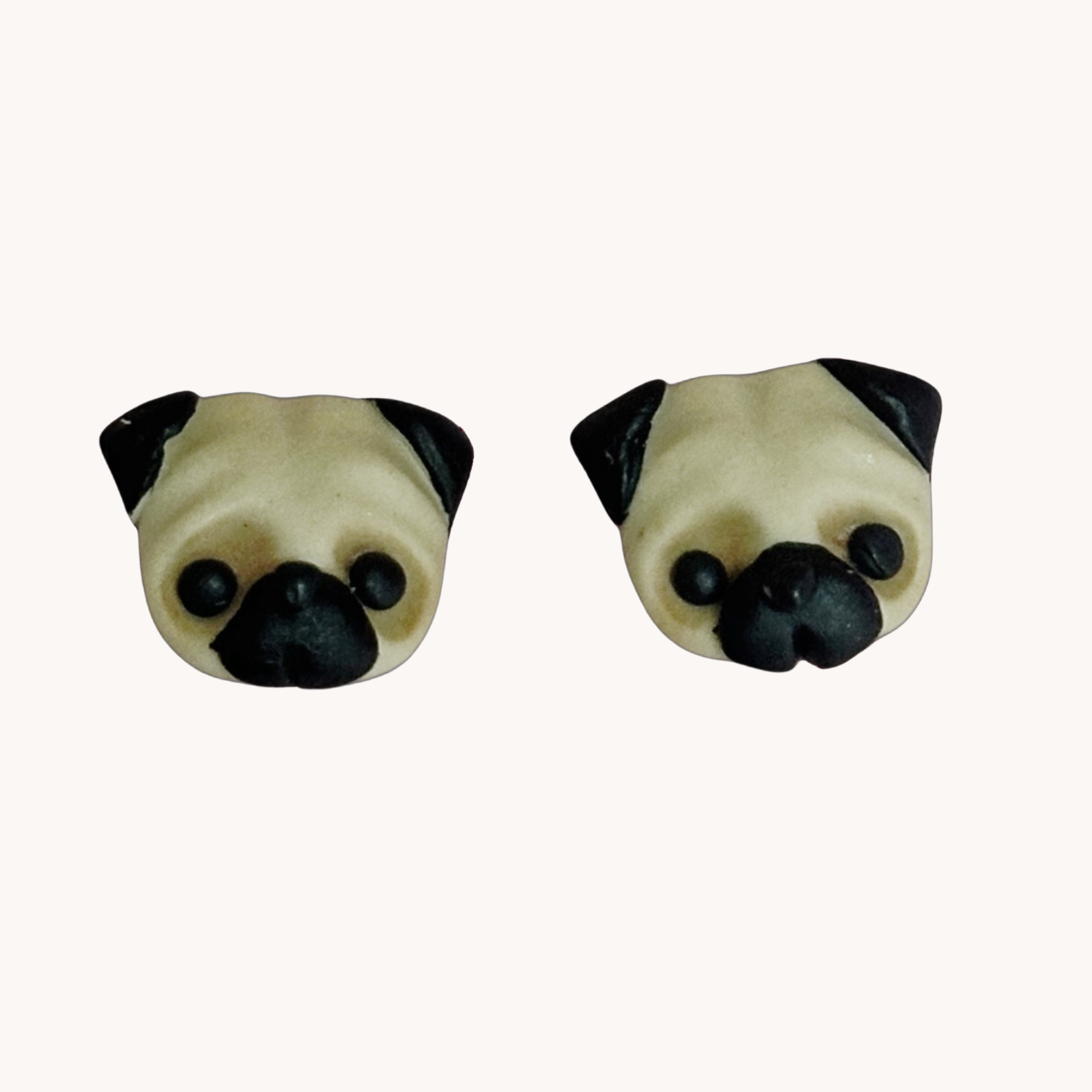 Two handmade polymer clay pug shaped earrings on a white background