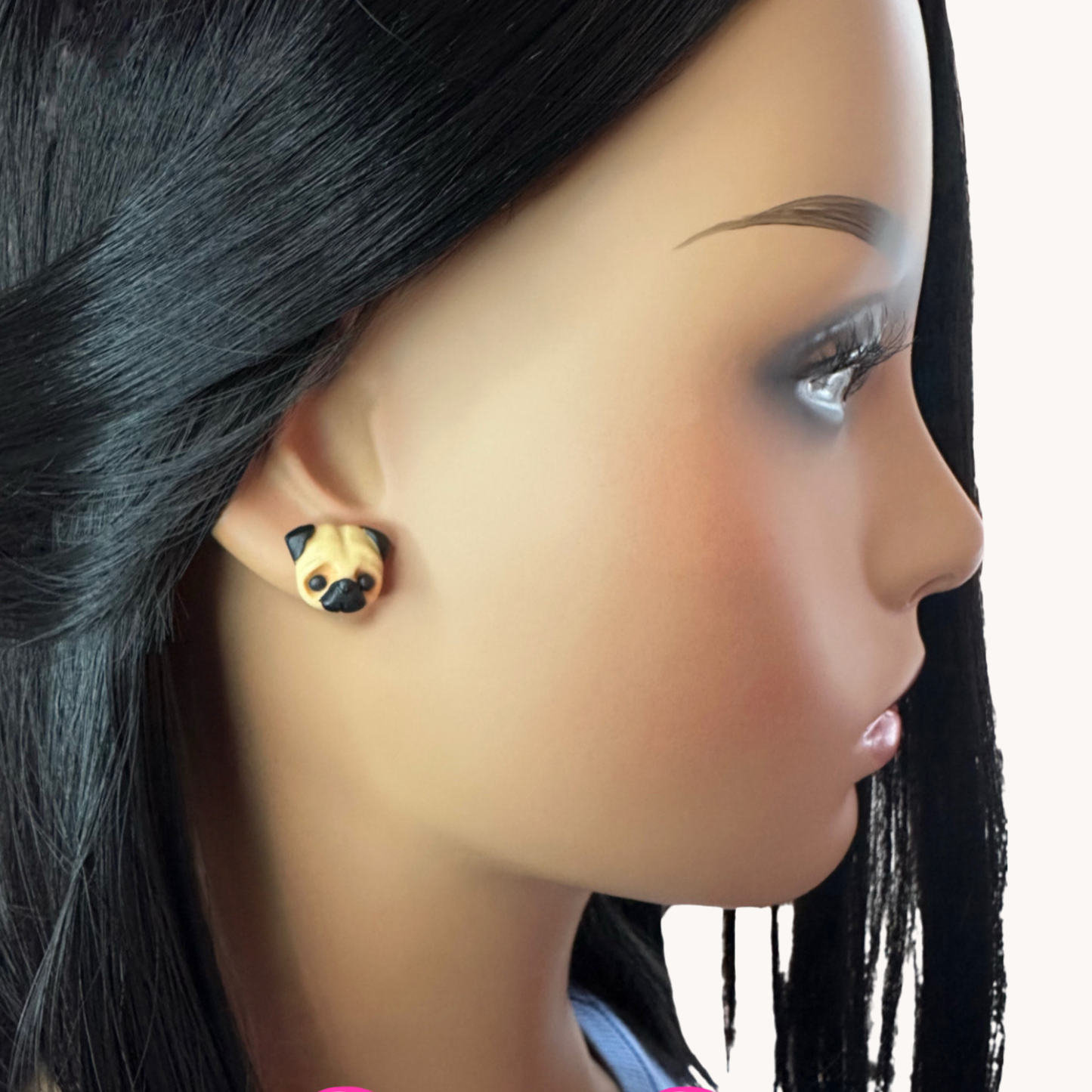Close-up of a mannequin head wearing handmade polymer clay pug-shaped earrings.