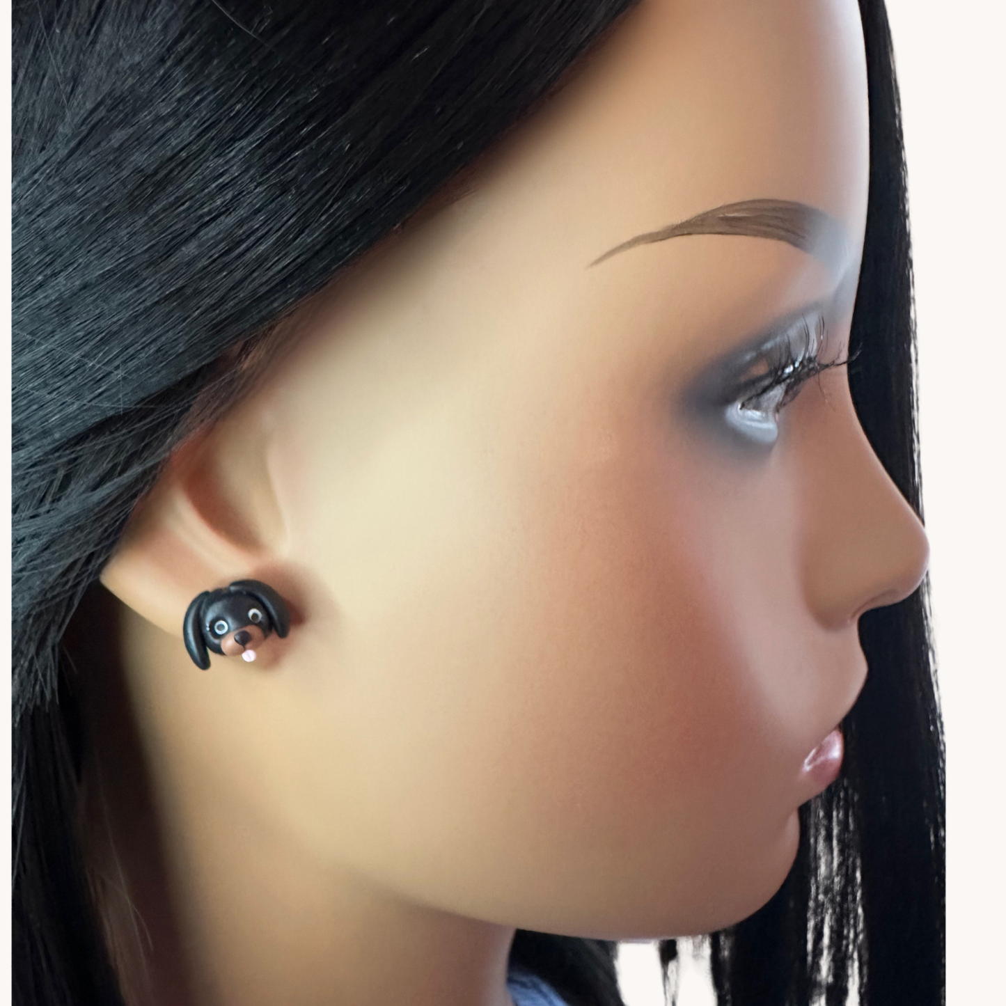 Close-up of a doll's head with black hair handmade polymer clay dachshund earrings